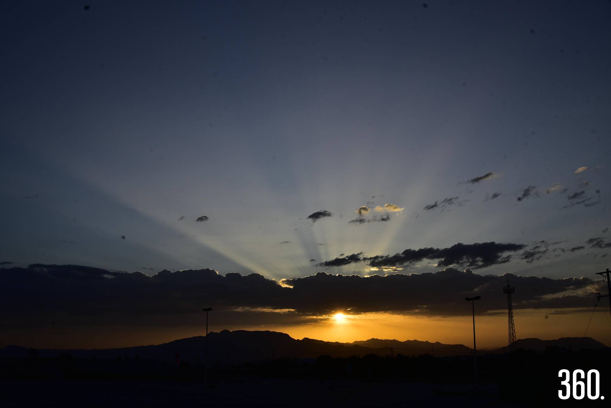 $!La ciudad se tiñe de tonos cálidos mientras el sol se esconde entre montañas y nubes.